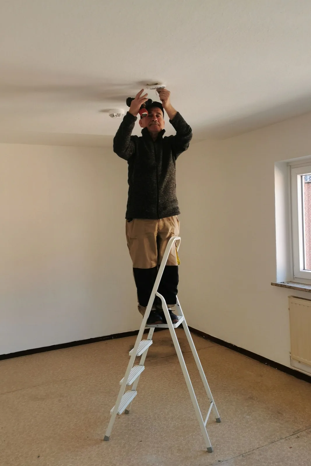 Fitting a ceiling detector from a step ladder, for ceiling fan installation in Surrey