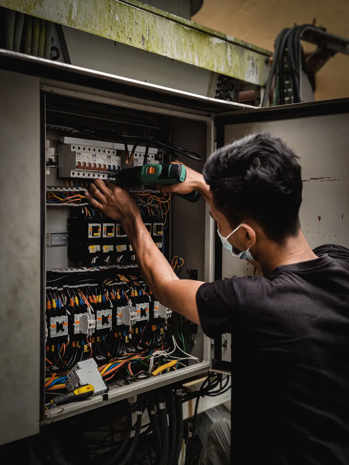 An electrician working inside a large distribution board, for commercial electrical in Surrey