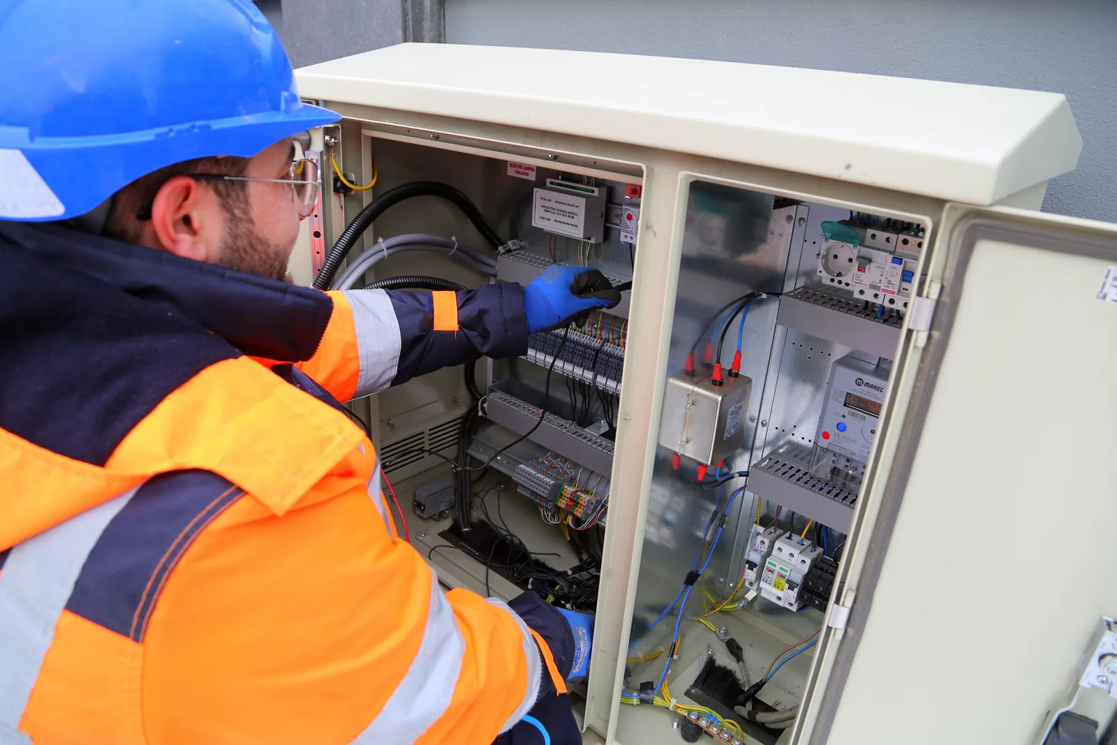 An electrician working in an outdoor service cabinet, for outdoor lighting in Surrey
